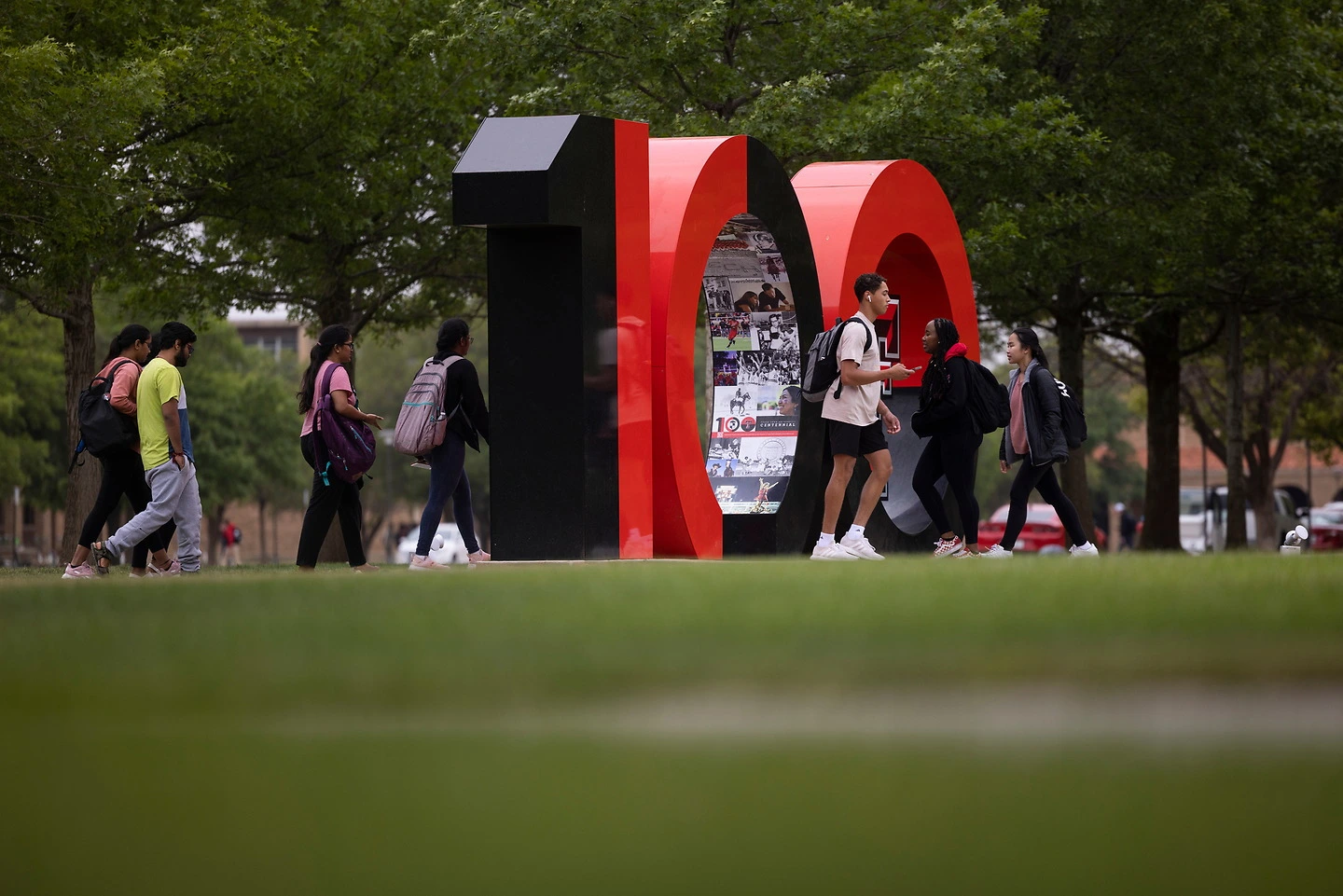 100 sign on campus with several students walking nearby.