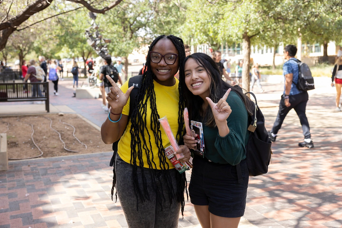 Two female students on campus posing with their hands.
