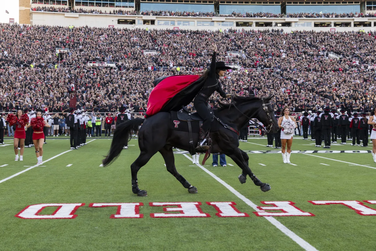 The Masked Rider on horseback galloping across the field at a Texas Tech football game