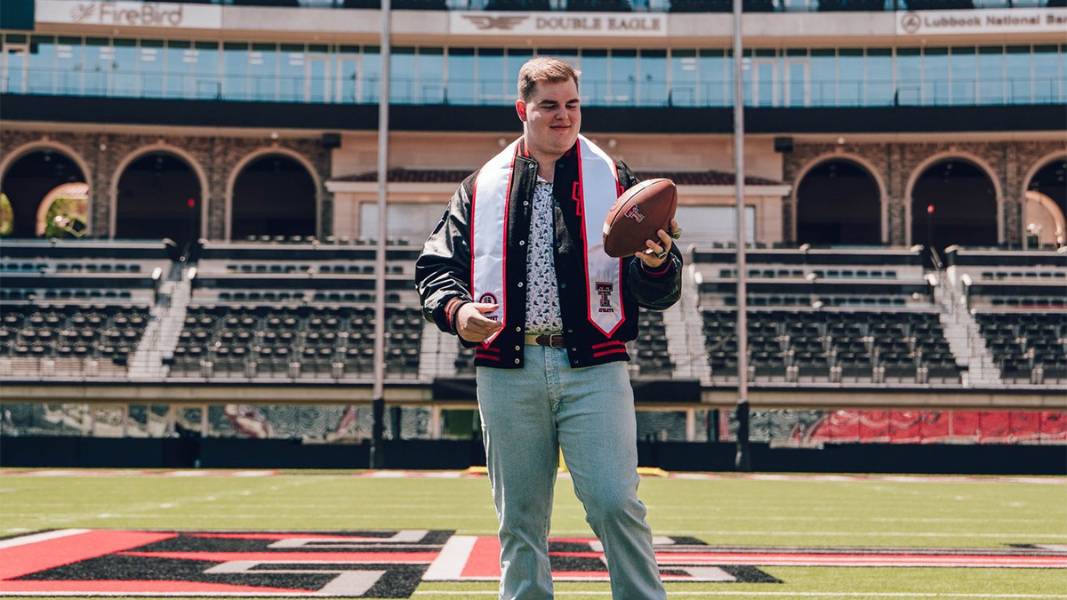 Jurrien Loftin holding a football in in the Texas Tech football stadium.