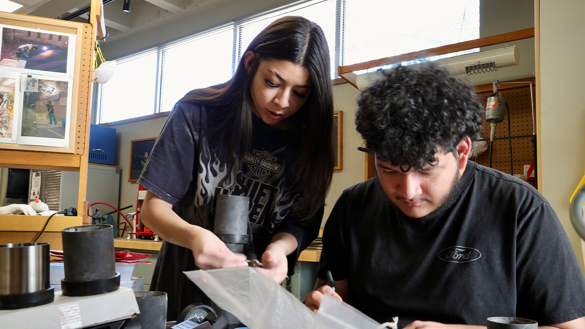 Ruby and Alex Santamaria side by side at their workbenches in the 3D Art Annex classroom.