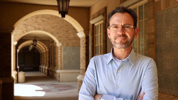 Glenn Cummins poses for a portrait along a campus archway