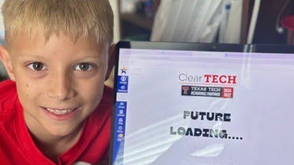 Young student poses beside a computer displaying ClearTECH and Texas Tech Academic Partner logos with the words “Future Loading.”