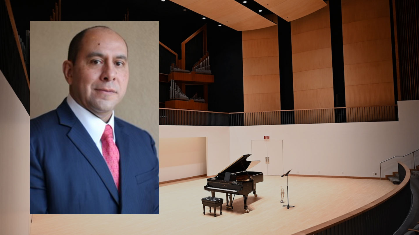 Portrait of Martin Camacho in a navy suit and red tie overlays a modern concert hall featuring a grand piano, organ pipes and warm wood paneling