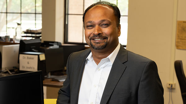 Ranadip Pal stands smiling in an office