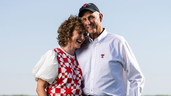 Barry and SuDe Street share a laugh while standing together in a cotton field, wearing Texas Tech apparel