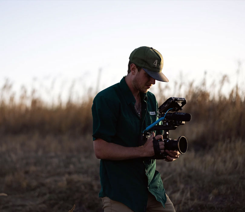 Male with camera surrounded by fields.