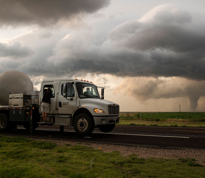 Doppler truck with tornado in the distance