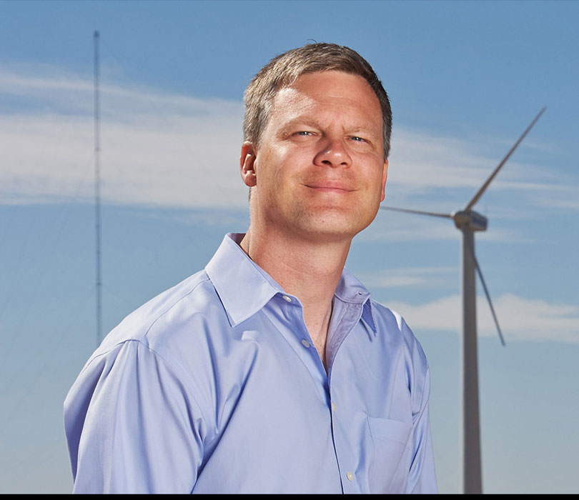John Schroeder with wind turbines in background