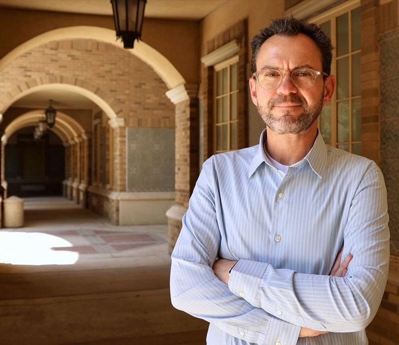 Glenn Cummins poses for a portrait along a campus archway.