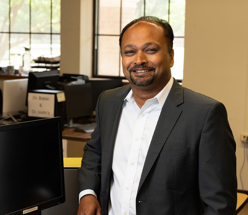 Ranadip Pal stands smiling in an office.