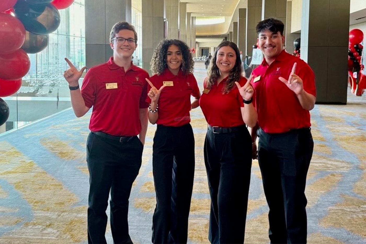 4 students posing with "Guns Up"