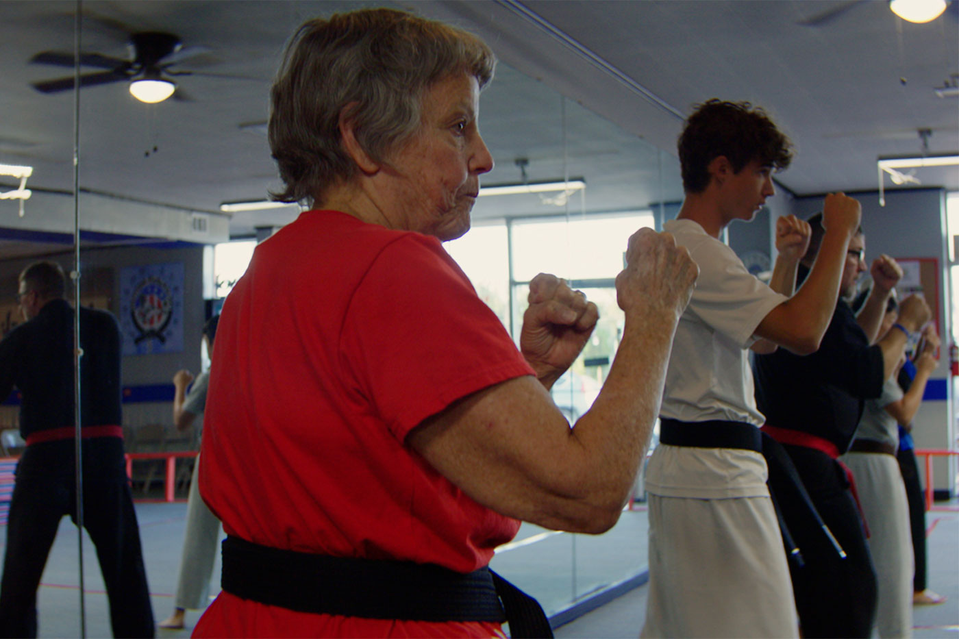 Judith in a karate stance, wearing a black belt.
