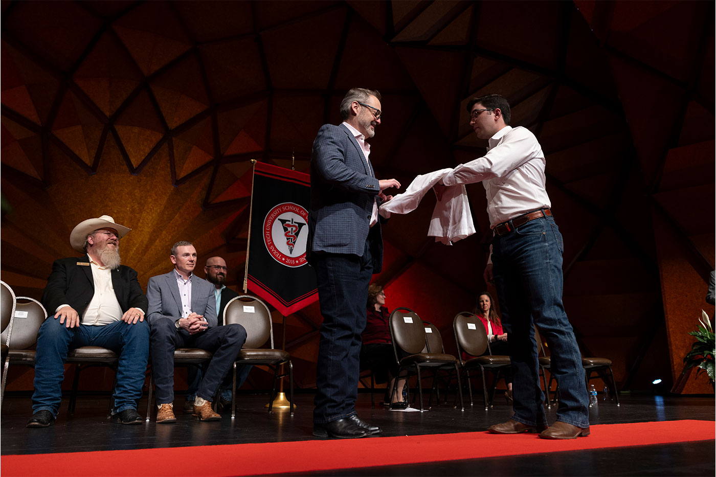 Guy Loneragan giving a white coat to a male student