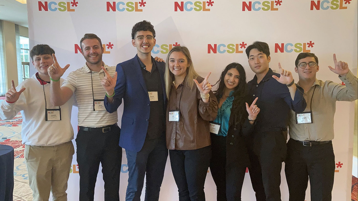 Roque and his colleagues in front of NCSL backdrop. 