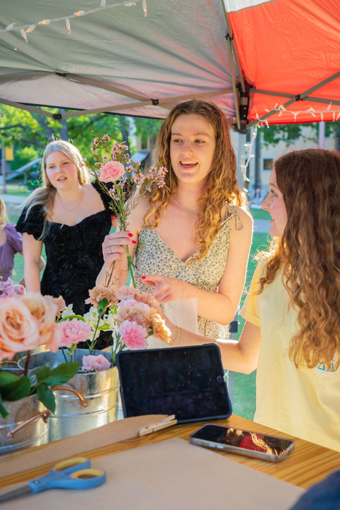 Young lady looking at flowers as two other females look on. 