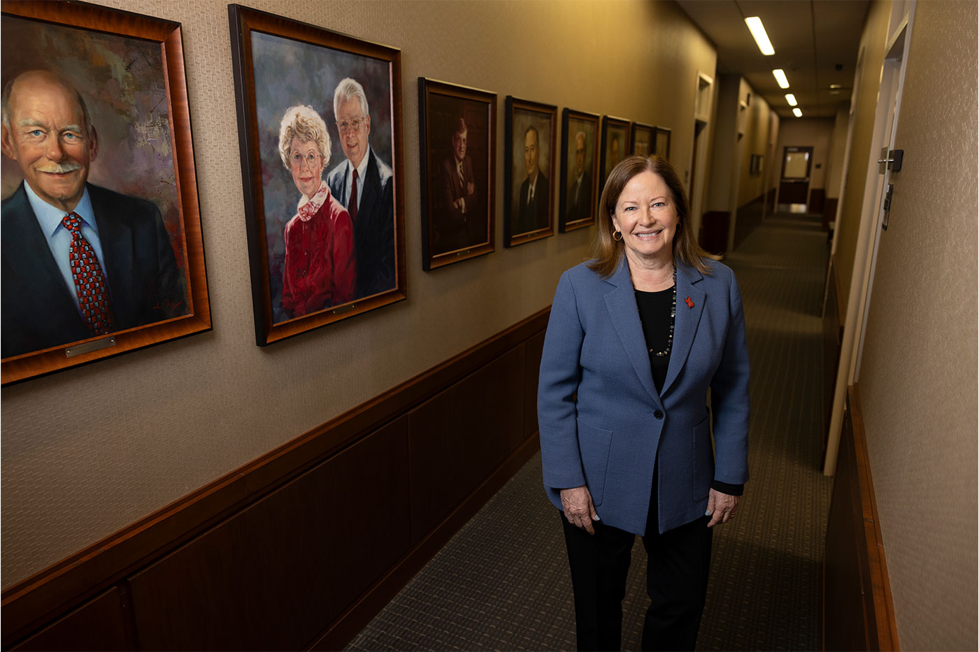 Margaret standing in a hallway lined with portraits. 