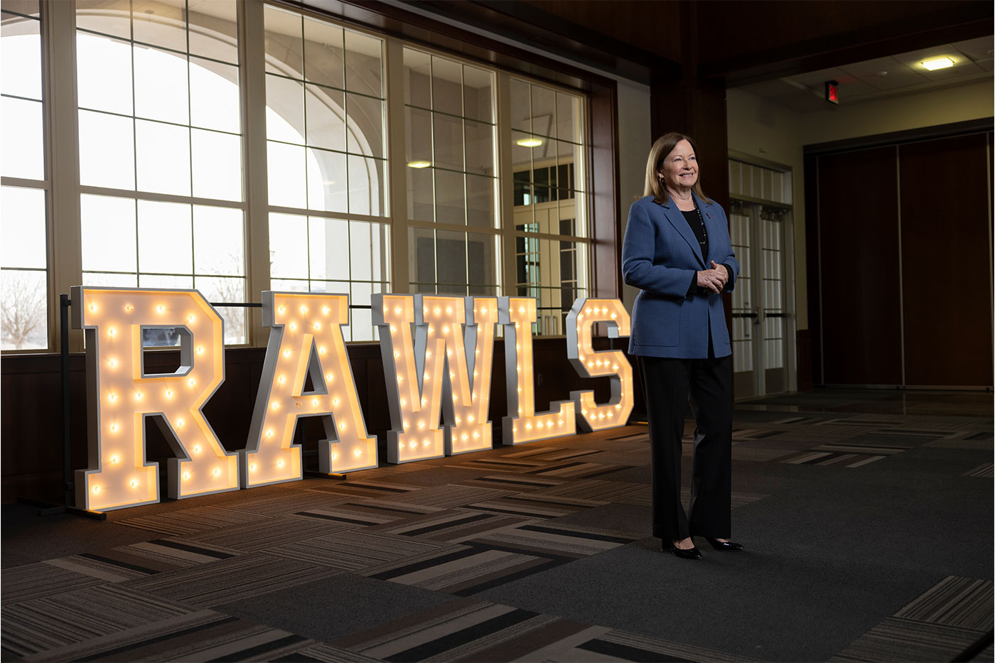 Margaret standing in front of a lit "Rawls" sign.