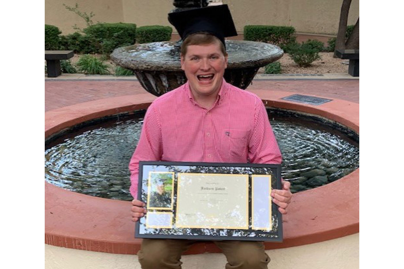 Jackson at the fountain, holding his diploma