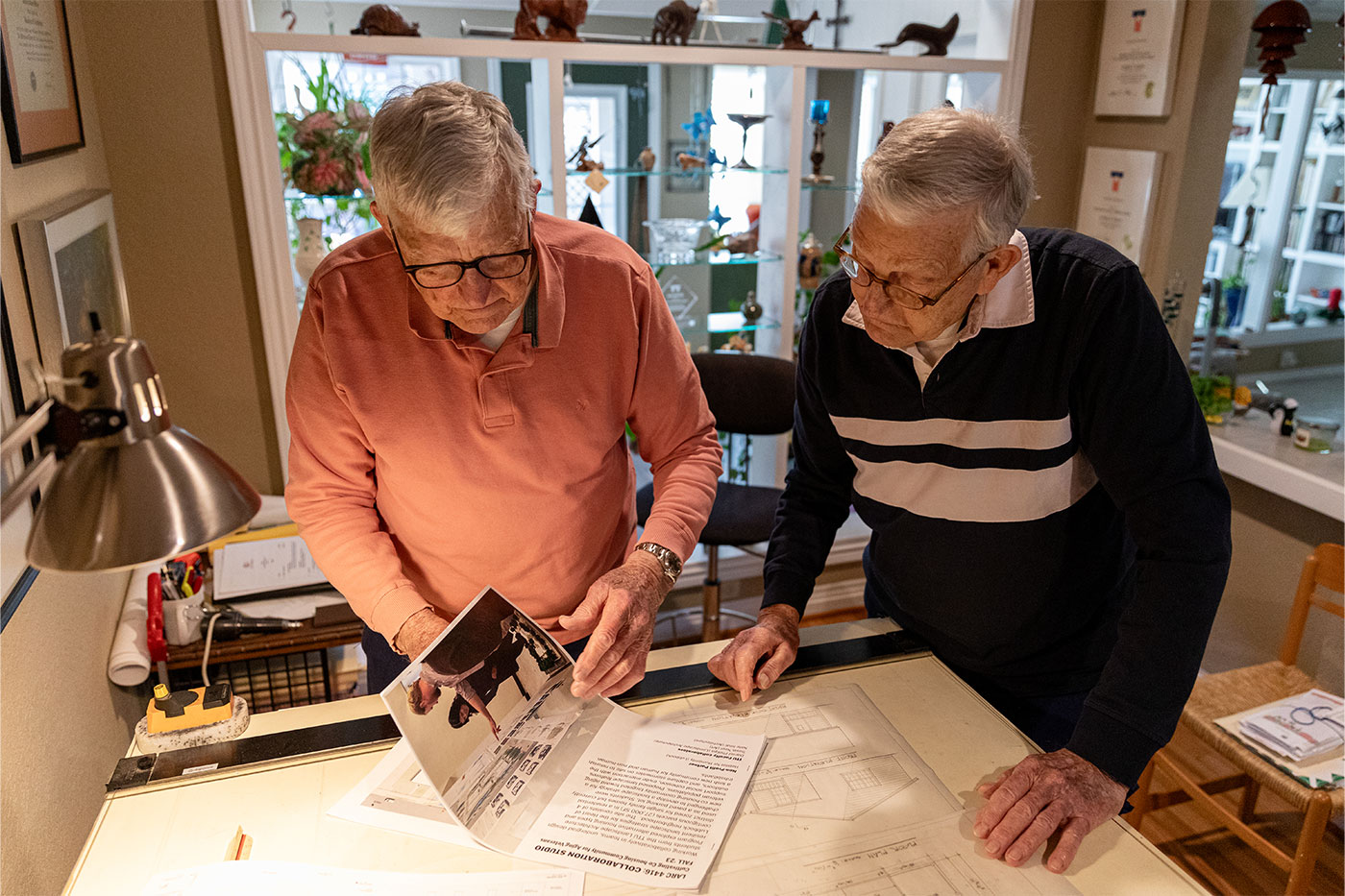 The brothers looking at something on a drafting table.