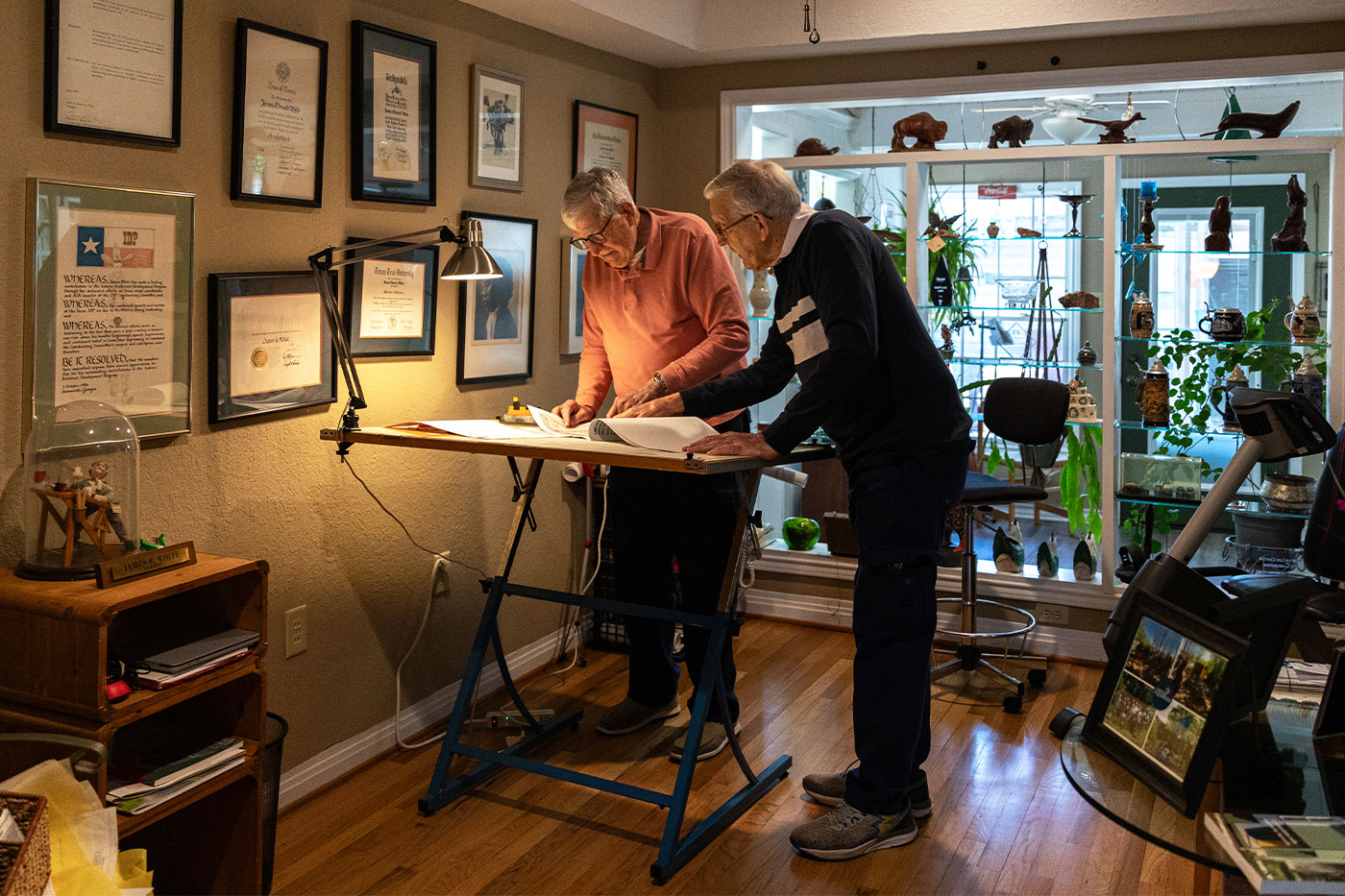 The brothers standing over a drafting table. (Wide shot of room)