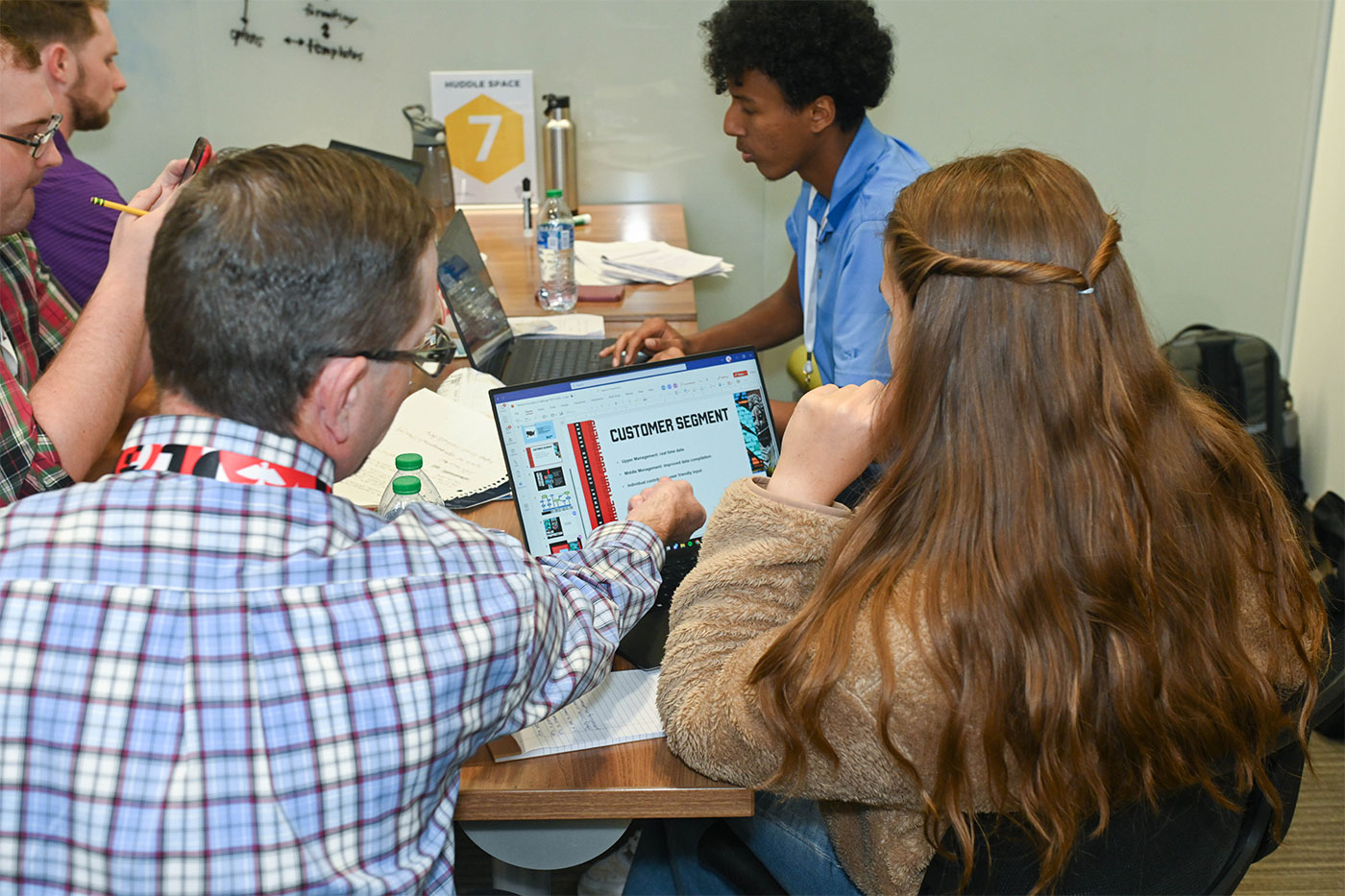 Looking over the shoulders of a man and student looking at a laptop computer. 