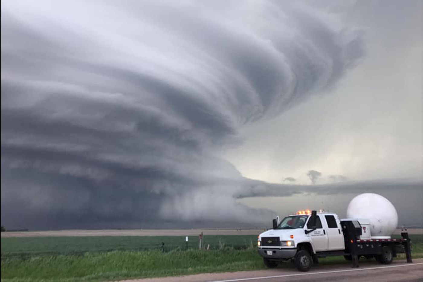 NWI Vehicle parked in front of a large tornado. 