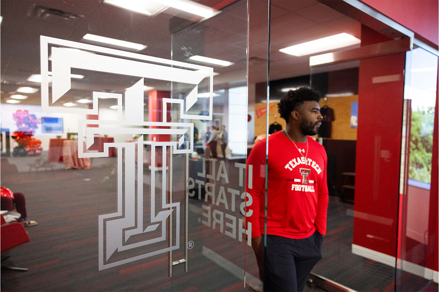 Man walking through a doorway, with double T on glass