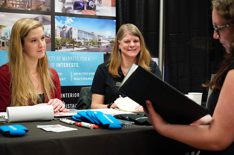 People talking at the architecture table at a career fair.