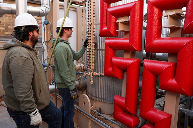 males with safety equipment working on chemical pipes