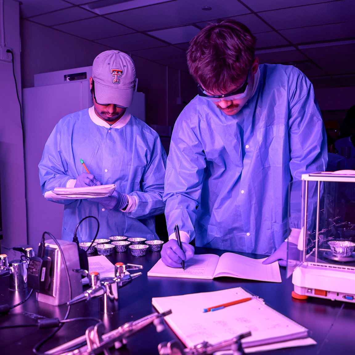 Two students write notes on an engineering project