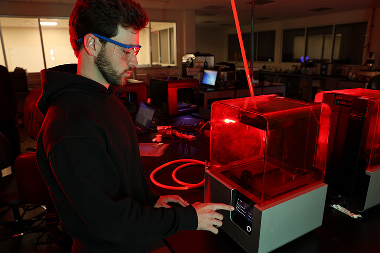 Student working with 3d printing equipment.