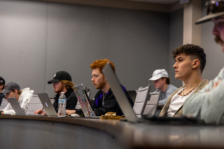 Students seated in a classroom with laptops.