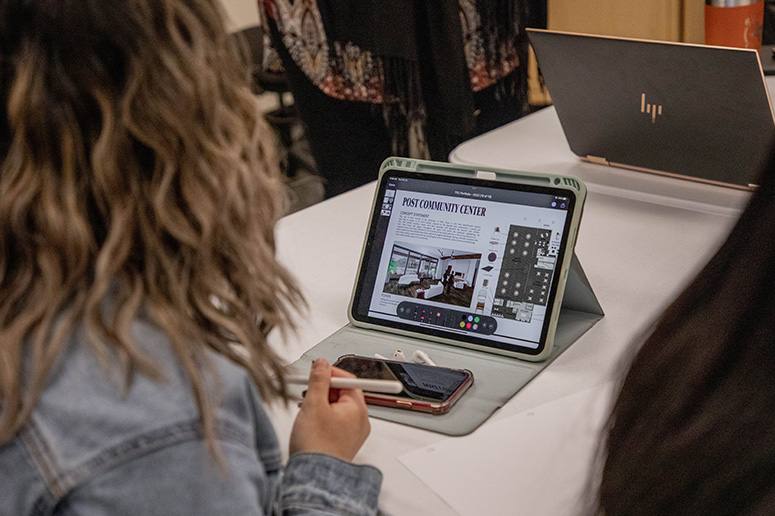 A student using a tablet computer with an interior design layout and 3D rendering.