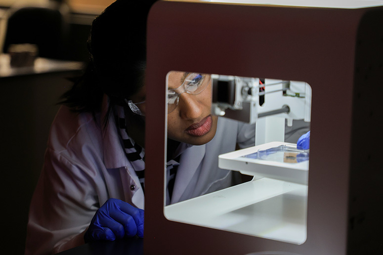 Student looking at materials inside a machine.
