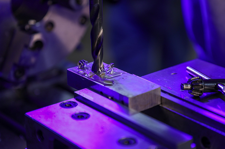 A machine drilling a hole in a piece of metal.