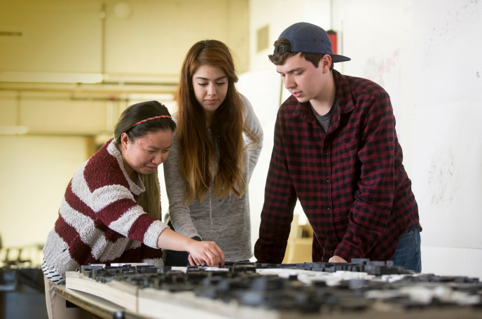 Three students examining and discussing.